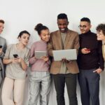 A multicultural team in professional attire working together with various digital devices indoors.