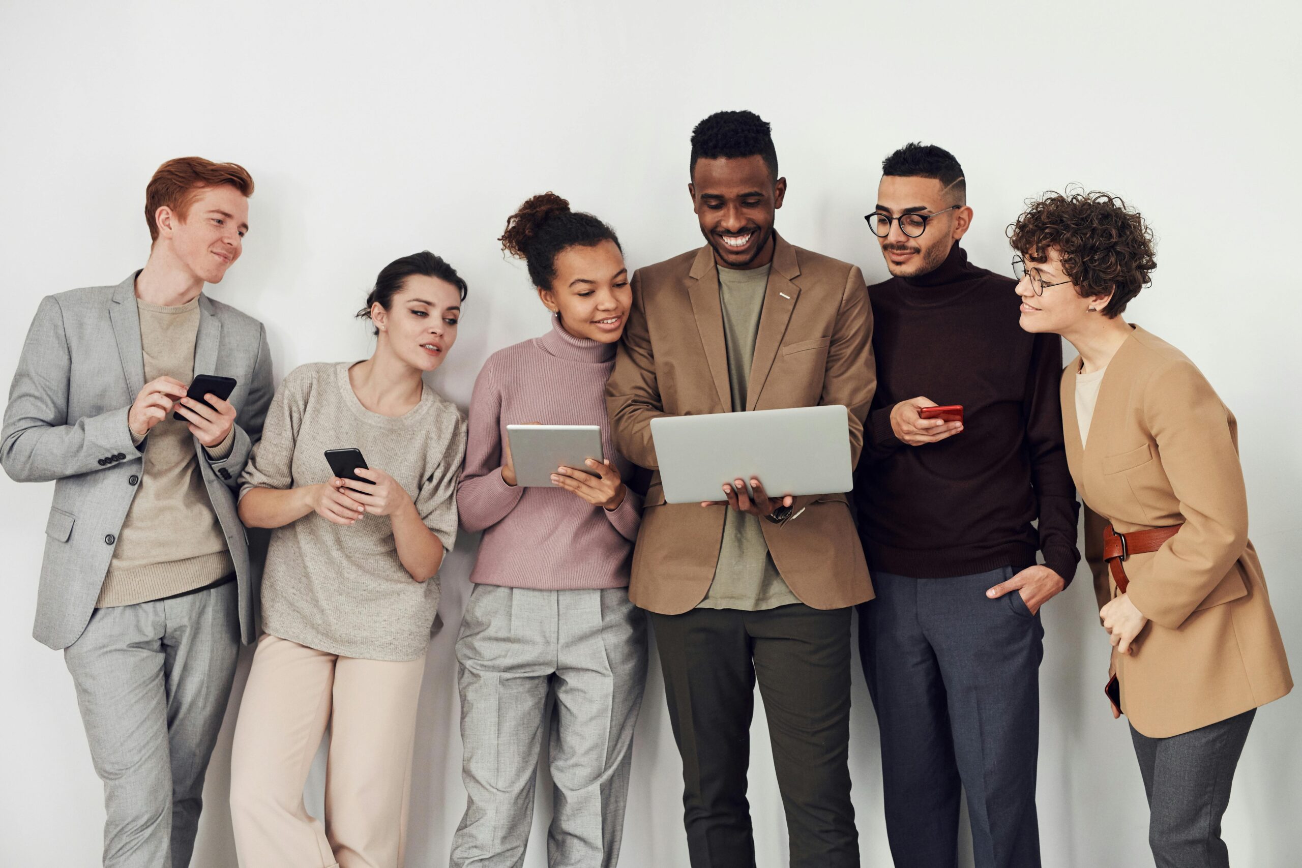 A multicultural team in professional attire working together with various digital devices indoors.